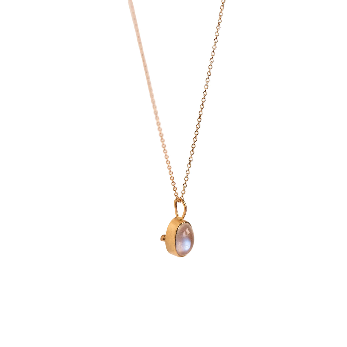 Gold necklace with a pendant on a light beige background
