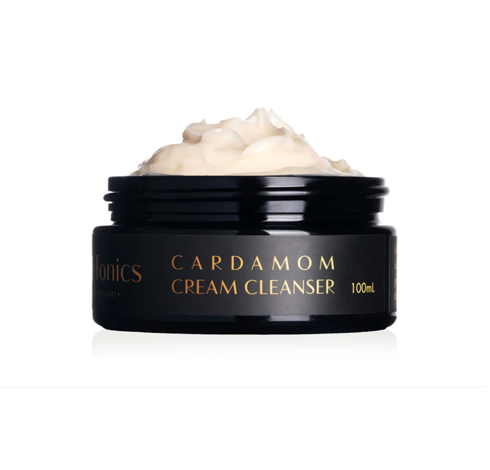 Black jar of Cardamom Cream Cleanser with cream visible on a white background