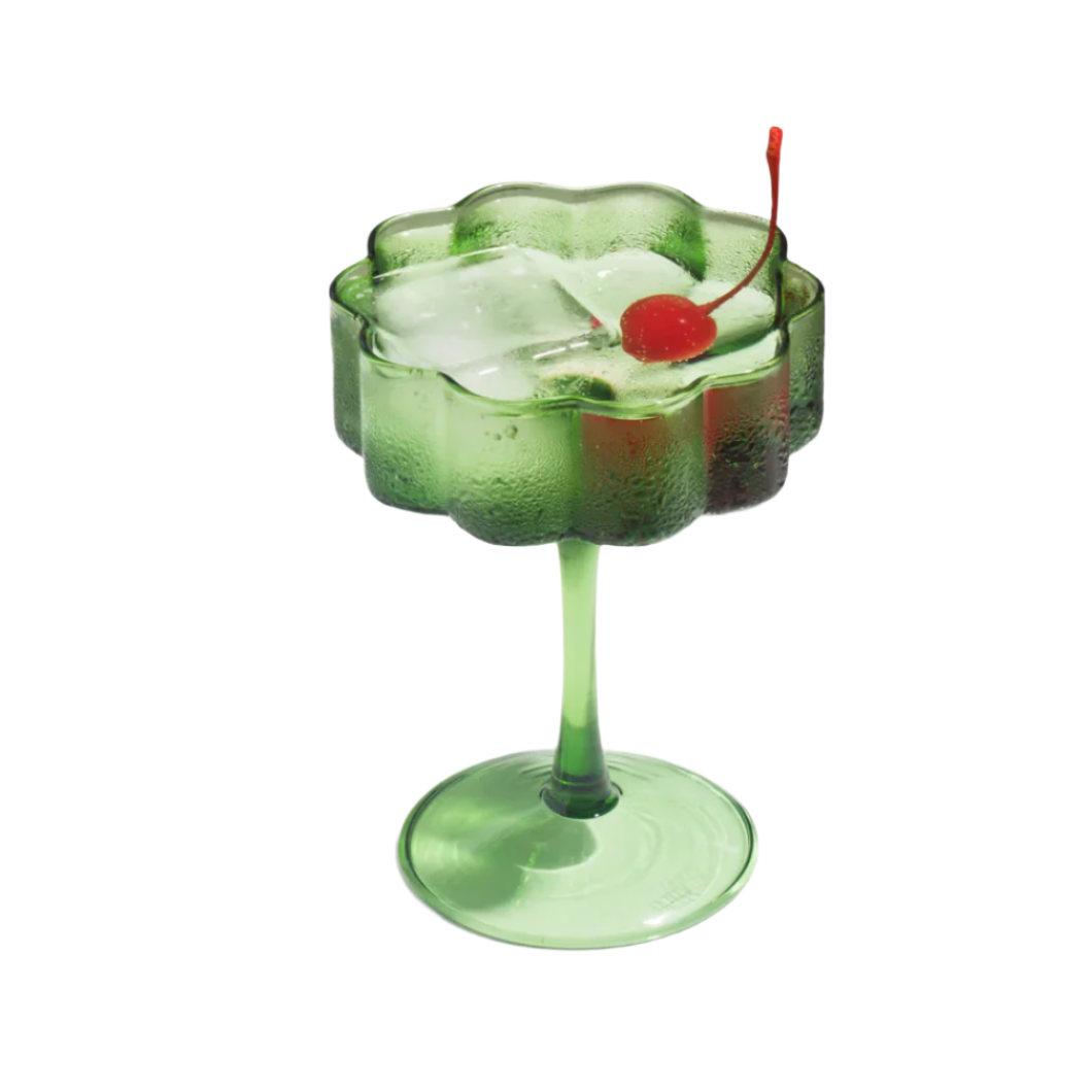 Green cocktail in a decorative glass with a cherry on a white background