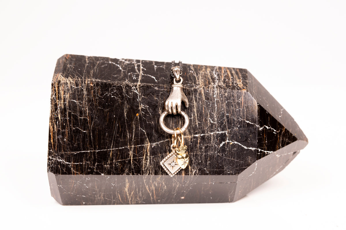 Black crystal with decorative hand and ring charm on a white background