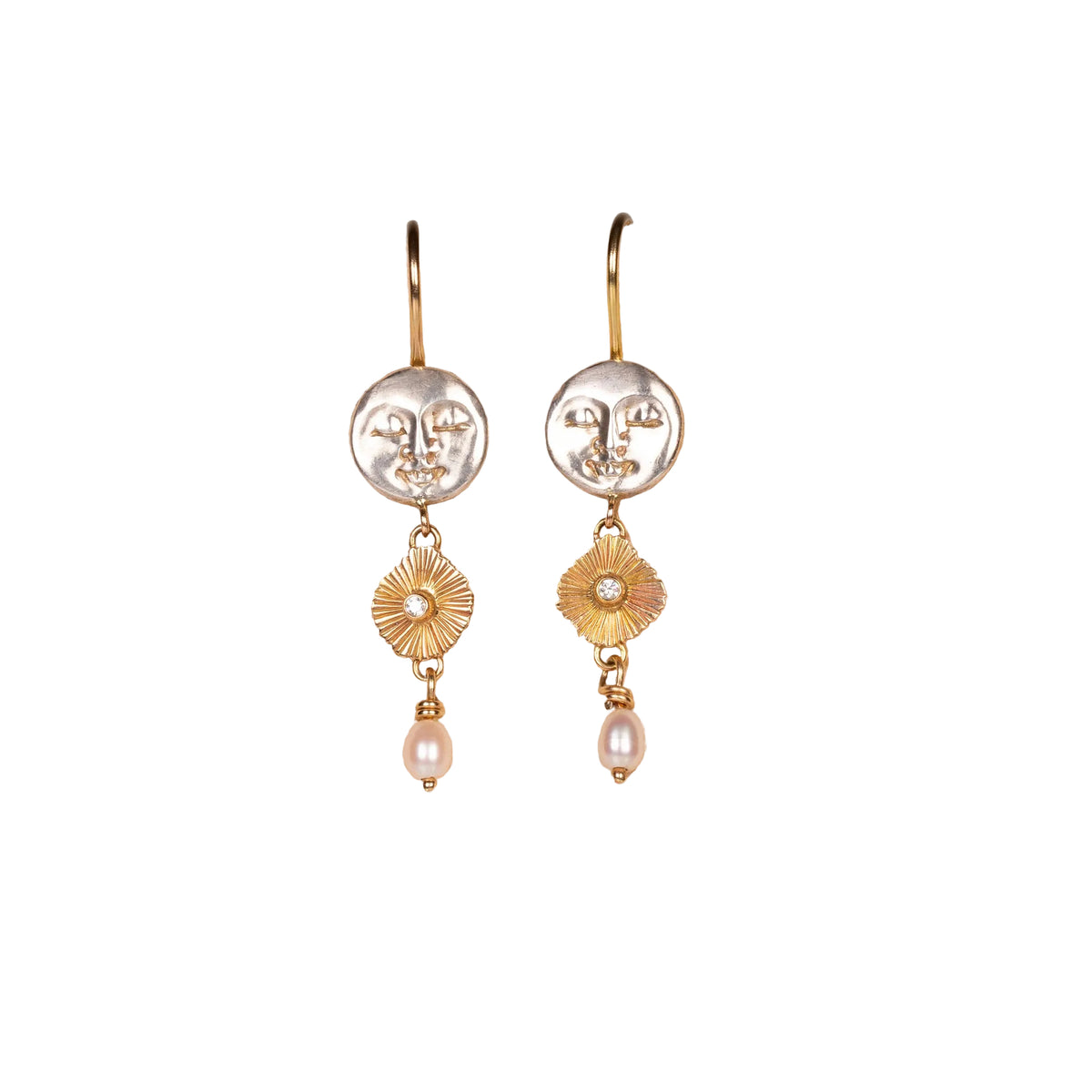 Pair of gold and silver earrings on a beige fabric background