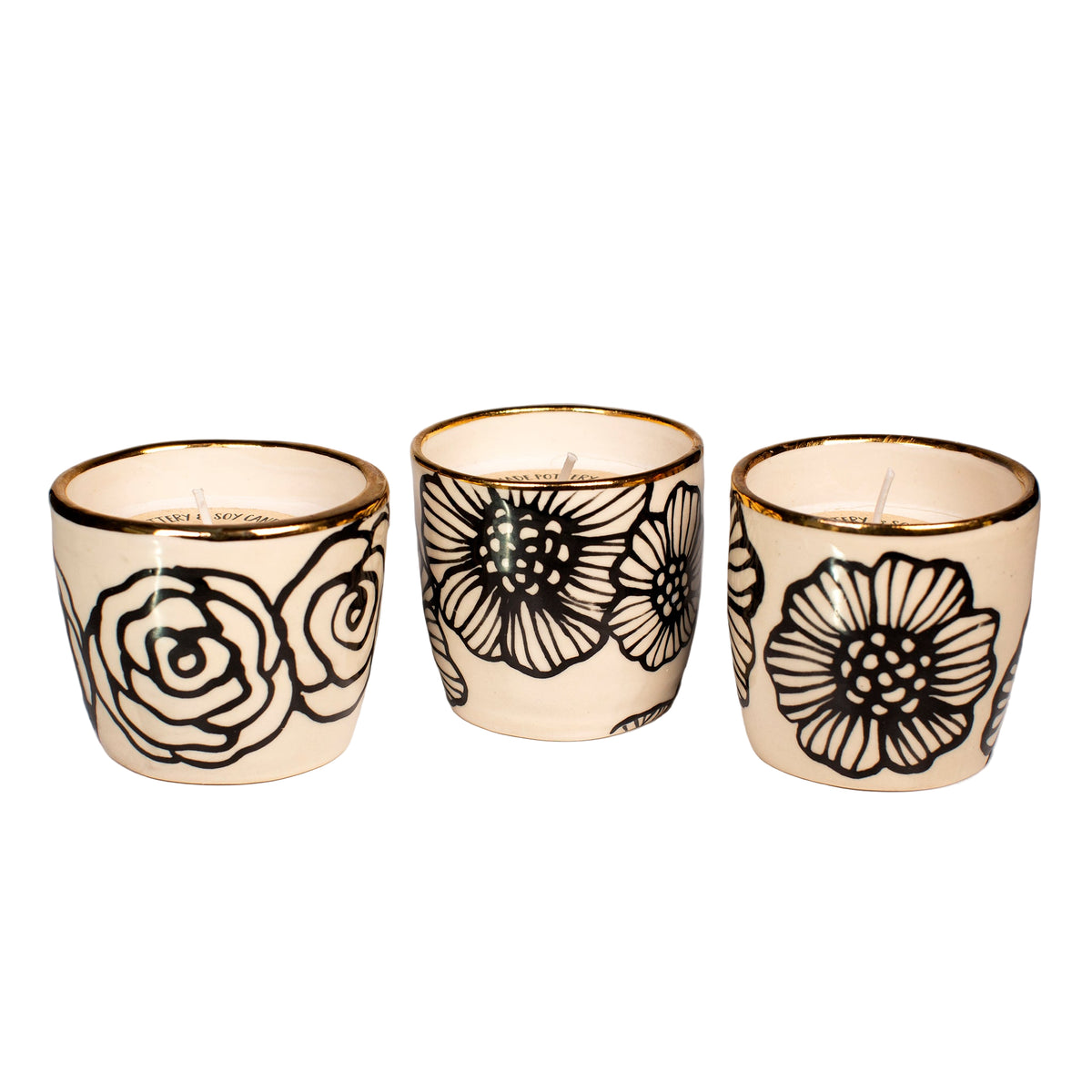 Three ceramic candle holders with floral designs on a white background