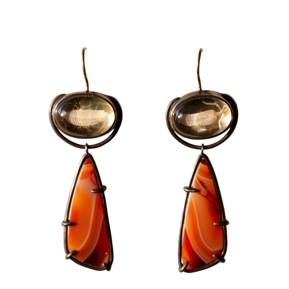 Pair of earrings with amber-colored stones on a beige background