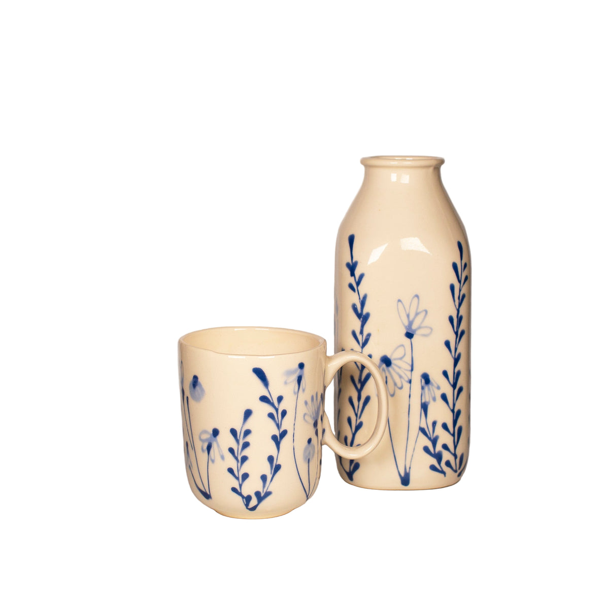 Ceramic mug and bottle with blue floral patterns on a neutral background